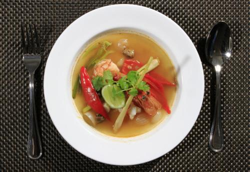 a bowl of soup with shrimp and vegetables on a table at Mars City Hotel in Denpasar