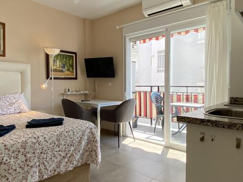 een hotelkamer met een bed, een bureau en een balkon bij Mariposa Studio Casasol in Nerja
