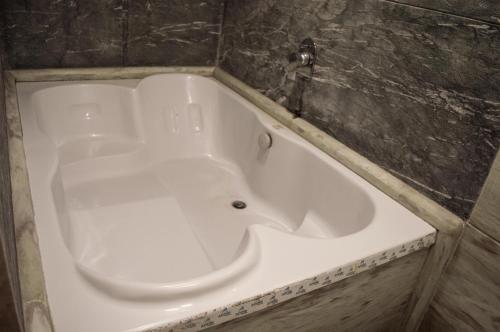 a white bath tub in a room with a wall at Prime Villa in Lonavala