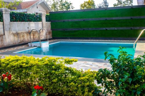 a swimming pool in a garden with a fence at Prime Villa in Lonavala