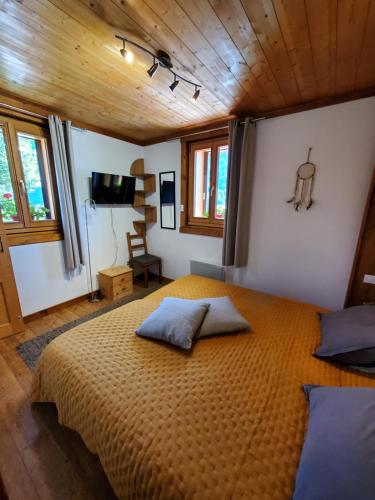 - une chambre avec un grand lit dans une pièce dotée de plafonds en bois dans l'établissement Chaleureux 2 pièces avec terrasse à Seez, à Séez