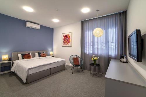 Schlafzimmer mit einem Bett, einem Tisch und einem TV in der Unterkunft Benefice Hotel Yerevan in Yerevan