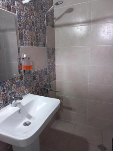 ein Badezimmer mit einem weißen Waschbecken und einer Dusche in der Unterkunft Bee House in Kilda
