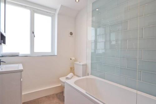 a bathroom with a tub and a toilet and a window at Hotwells Modern Mews in Bristol