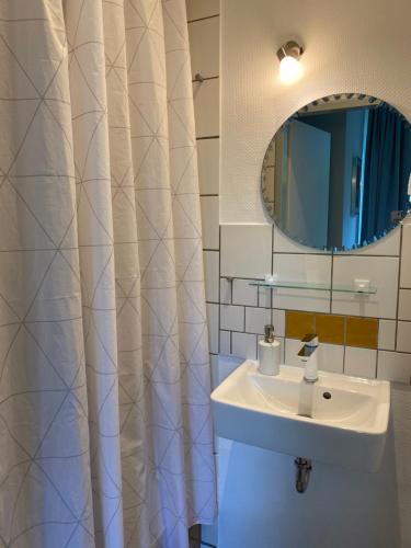 W białej łazience znajduje się umywalka i lustro. w obiekcie Zentrale Ferienwohnung mit Balkon in Aachen w Akwizgranie