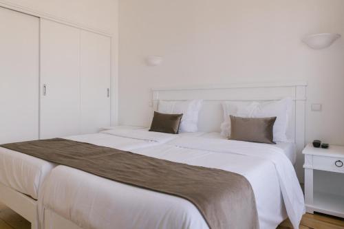 a white bedroom with a large white bed at Quinta do Eden in Vagos