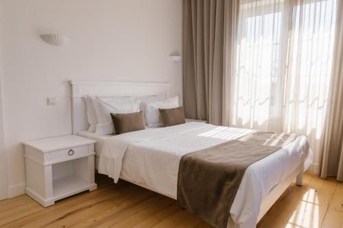 a white bedroom with a large bed and a window at Quinta do Eden in Vagos