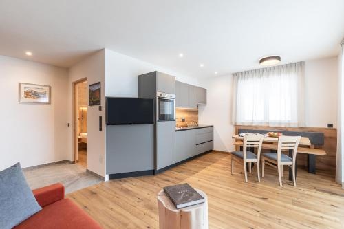 cocina y sala de estar con mesa y nevera en Baumannhof en Funes