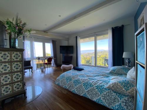 ein Schlafzimmer mit einem Bett und einem großen Fenster in der Unterkunft Petite maison à l'orée des bois vue magnifique sur le lac zenitude et plénitude in Belmont-sur-Lausanne