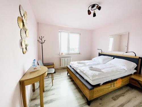 a bedroom with a large bed and a table at MS Pro Apartamenty Chodkiewicza (Uzdrowisko) in Kołobrzeg