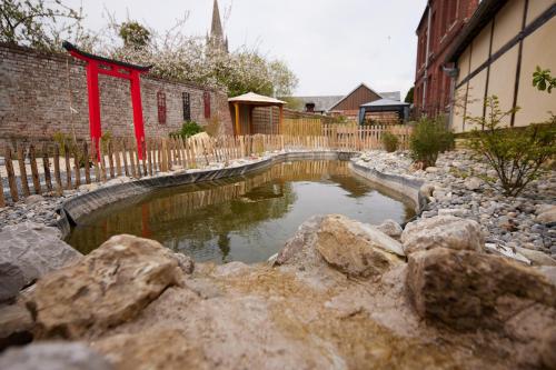 a small pond in a yard with rocks at L'Antre de Gadag in Forges-les-Eaux
