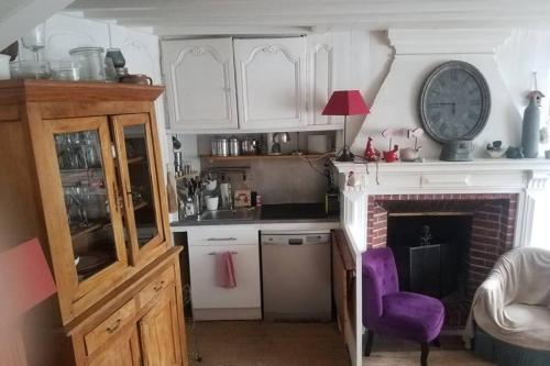 une cuisine avec une cheminée et une horloge murale dans l'établissement la maison de Caroline, à Saint-Valery-en-Caux