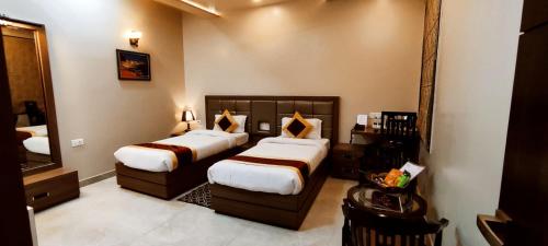 Una habitación de hotel con dos camas y un espejo. en Hotel Ozas Grand, en Varanasi