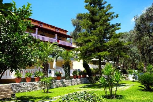 a house in a garden with trees and plants at Magda's Hotel Apartments in Parga