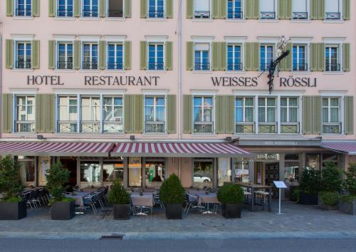 a hotel with tables and chairs in front of a building at Weisses Rössli Swiss Quality Hotel in Brunnen