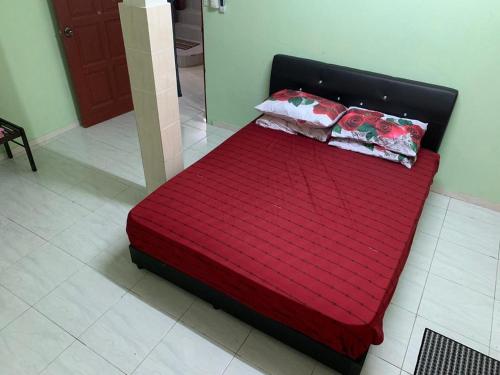 Una cama roja con dos almohadas encima. en Homestay DI Kota Samarahan, en Kota Samarahan