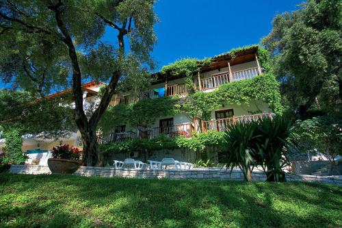 a building with trees and chairs in front of it at Magda's Hotel Apartments in Parga