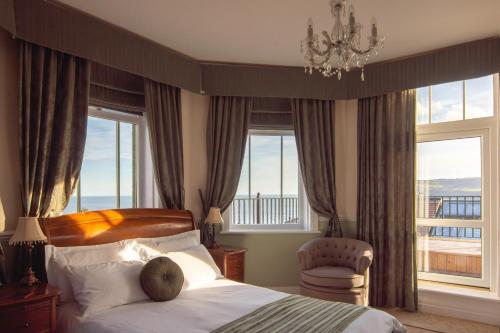 a bedroom with a bed and a chandelier and windows at Victoria Hotel in Whitby