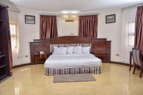 a bedroom with a large bed with a wooden headboard at Sonia Hotel in Accra