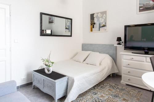 une chambre blanche avec un lit et une télévision dans l'établissement Studio en centre ville à 10 mn à pied de la gare, à Vannes