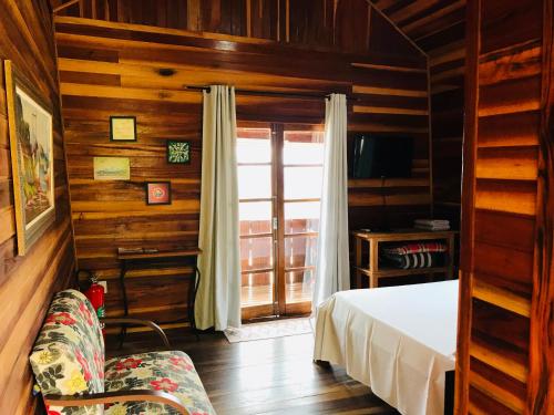 - une chambre avec un lit, une fenêtre et un canapé dans l'établissement Chalé da Montanha - Locações, à Águas de Lindóia