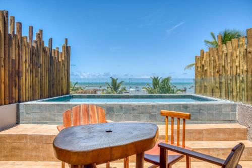 a table and chairs on a patio with a swimming pool at Pousada de Charme Villa Italiana - Pé na Areia in São Miguel dos Milagres