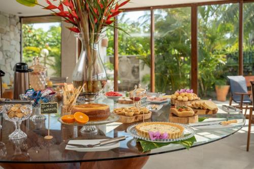 une table en verre avec des gâteaux et autres desserts dessus dans l'établissement Pousada Villa Italiana, à São Miguel dos Milagres