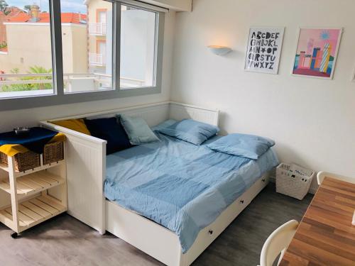 un letto con cuscini blu in una stanza con finestra di Bel appartement bord de mer 4 pers Arcachon centre ad Arcachon