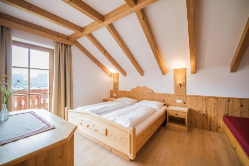 a bedroom with a wooden bed and a table at Klaudehof in Dobbiaco