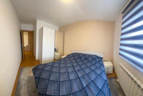 a bedroom with a bed with a blue comforter at Ognjen Apartman in Donje Mladice