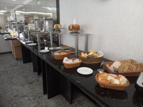 a long buffet line with baskets of bread and pastries at Hotel Nacional Inn Recife Aeroporto in Recife