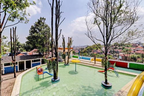 a swimming pool with trees and a playground at Collection O 90617 Rumah Oma Opa Syariah in Bandung