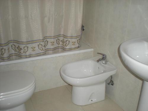 a white bathroom with a toilet and a sink at Pension Vagalume in Boiro