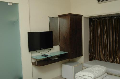 Hotel Causeway, Colaba في مومباي: غرفة معيشة مع تلفزيون بشاشة مسطحة على جدار