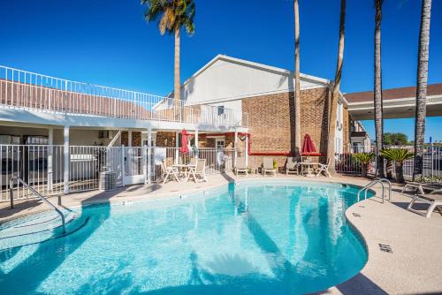 a large swimming pool with palm trees in a resort at Studio 6 Tucson, AZ - North in Tucson