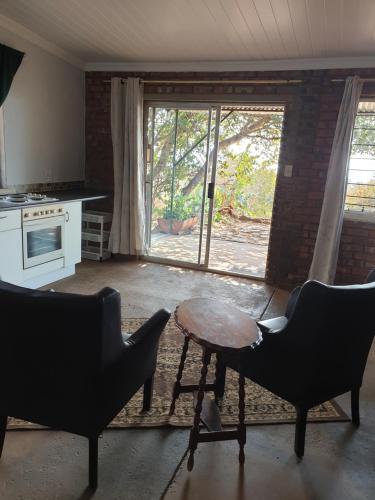 eine Küche mit 2 Stühlen, einem Tisch und einem Fenster in der Unterkunft Dombeya Ridge Guest Suite in Rustenburg