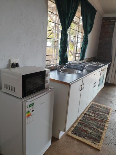 a kitchen with a microwave on top of a refrigerator at Dombeya Ridge Guest Suite in Rustenburg
