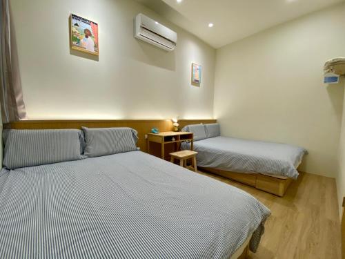 a bedroom with two beds and a table with a night stand at 高雄好日子914包棟KTv民宿 in Kaohsiung