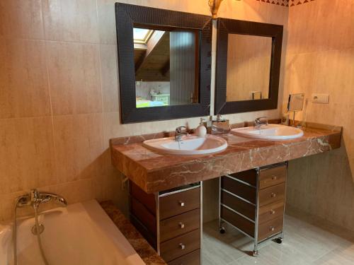 a bathroom with two sinks and a mirror and a tub at Badaguás (Jaca) - Duplex en el Pirineo in Jaca