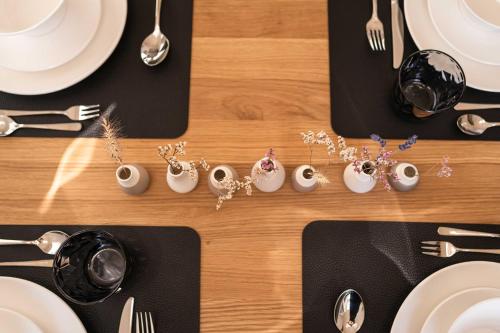 a table with white plates and forks and spoons at Weinberg Chalet Klöch in Klöch