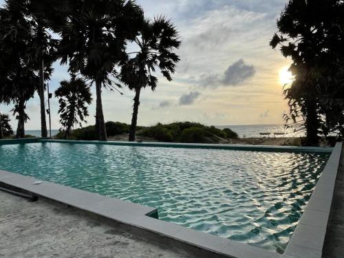 uma piscina com palmeiras e o oceano em Majestic Beach Retreat em Kalpitiya