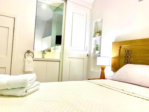 a white bedroom with a bed and a mirror at Casa Rambla Serra Cali in Cali