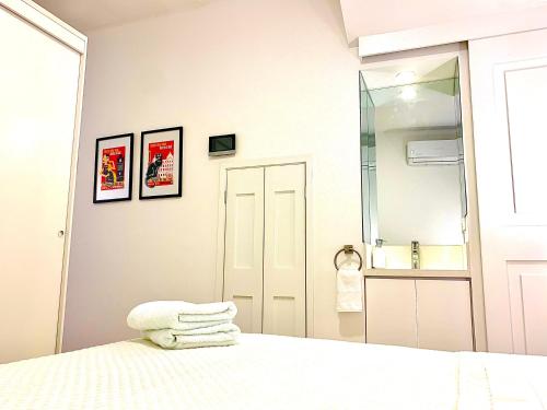 a white bedroom with a bed and a mirror at Casa Rambla Serra Cali in Cali