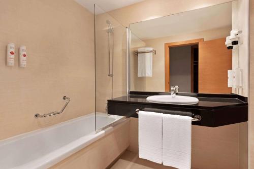 a bathroom with a sink and a bath tub at Ramada by Wyndham Valencia Almussafes in Almussafes