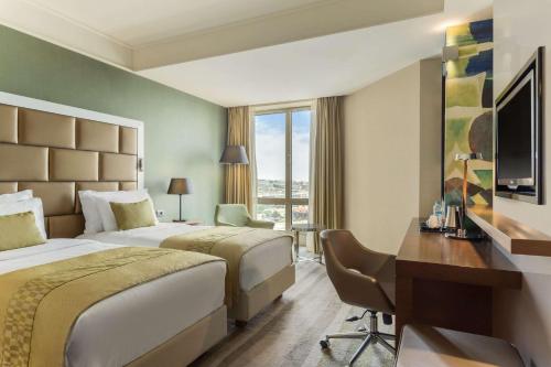a hotel room with two beds and a desk at Wyndham Grand Istanbul Europe in Istanbul