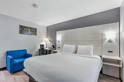 a bedroom with a large bed and a blue chair at Days Inn by Wyndham Savannah Gateway I-95 in Savannah