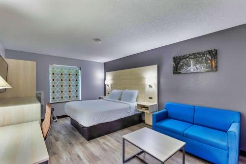 a hotel room with a bed and a blue couch at Days Inn by Wyndham Savannah Gateway I-95 in Savannah