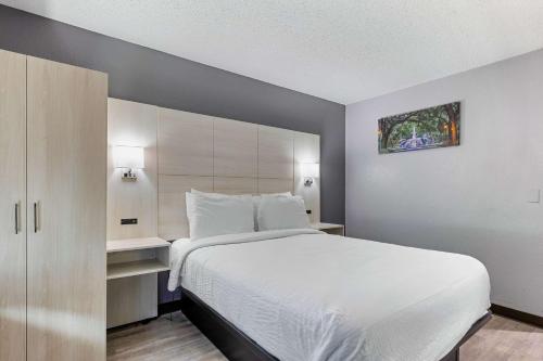 a bedroom with a large white bed and a cabinet at Days Inn by Wyndham Savannah Gateway I-95 in Savannah