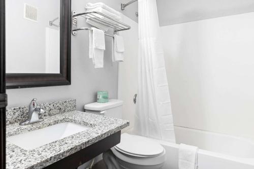 a bathroom with a sink and a toilet and a mirror at Days Inn by Wyndham Savannah Gateway I-95 in Savannah