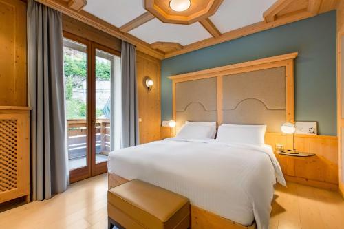 una camera da letto con un grande letto bianco e una finestra di Radisson Residences Savoia Palace Cortina d’Ampezzo a Cortina dʼAmpezzo